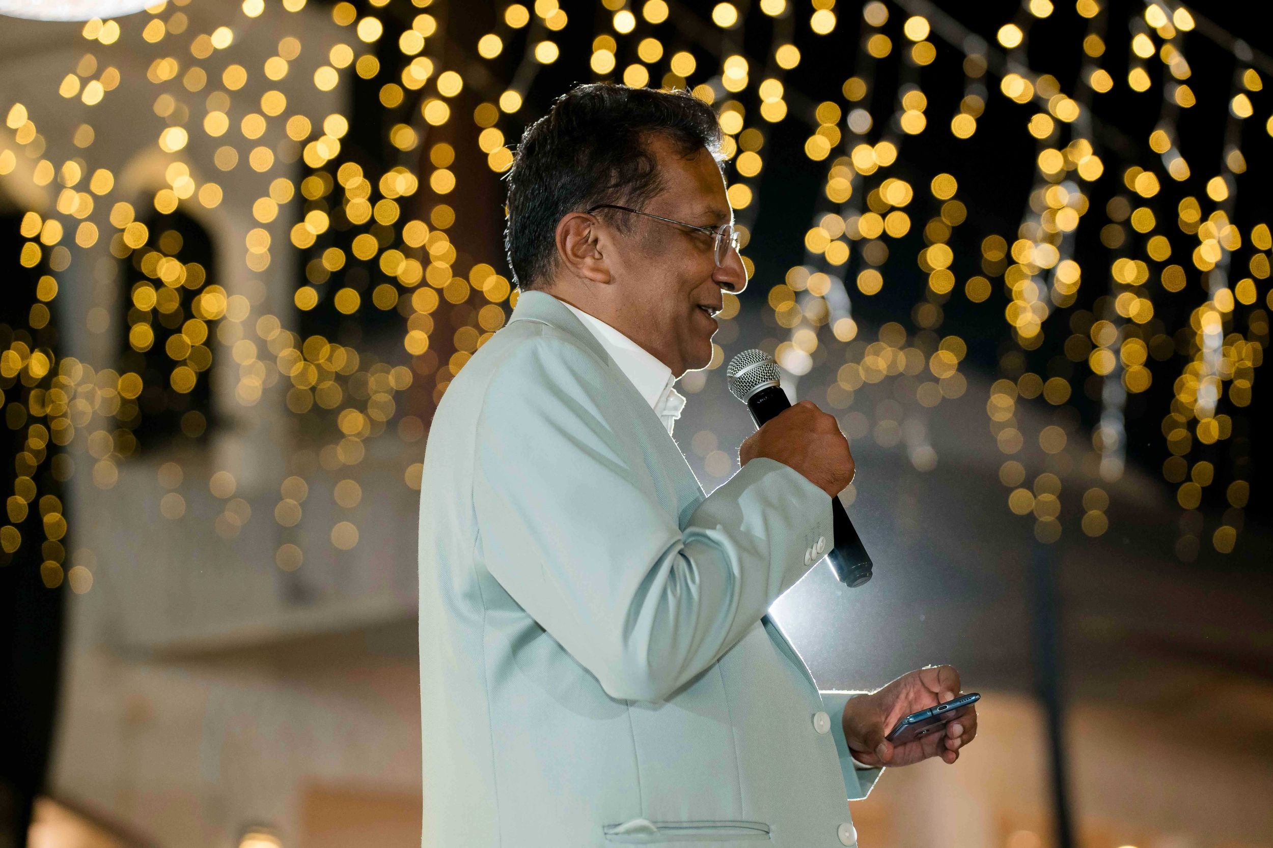 People celebrating at an evening wedding reception with glowing bokeh lights in the background.