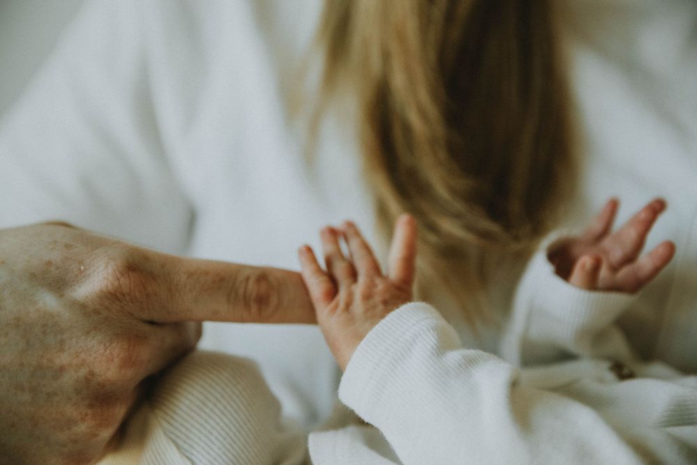 Small hands reach out and touch one another in an intimate family moment against a white background.