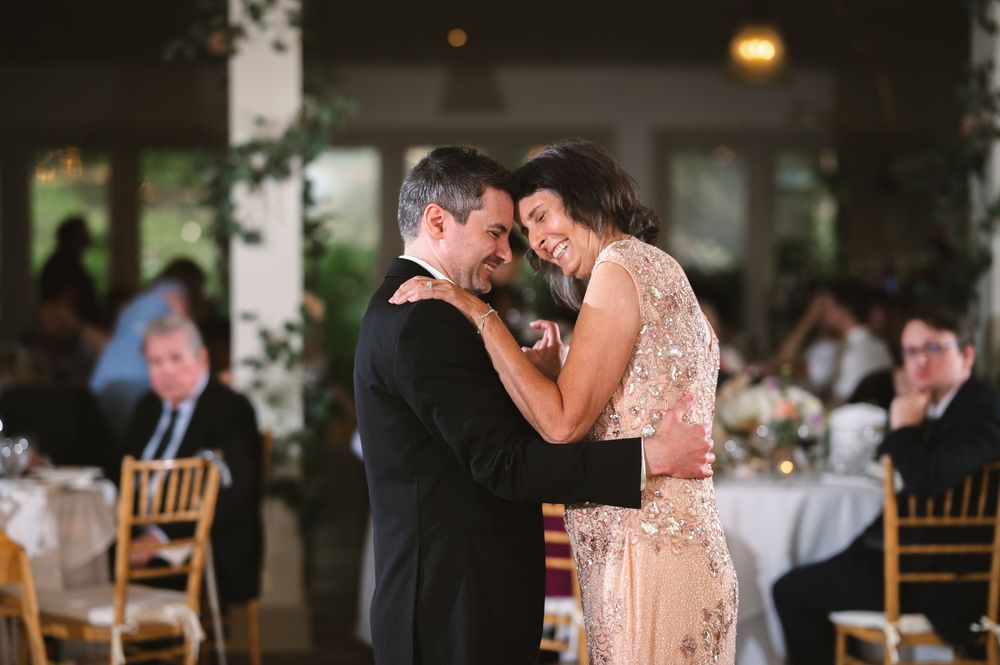 A romantic couple shares a tender moment on the dance floor at an elegant reception venue in soft lighting.