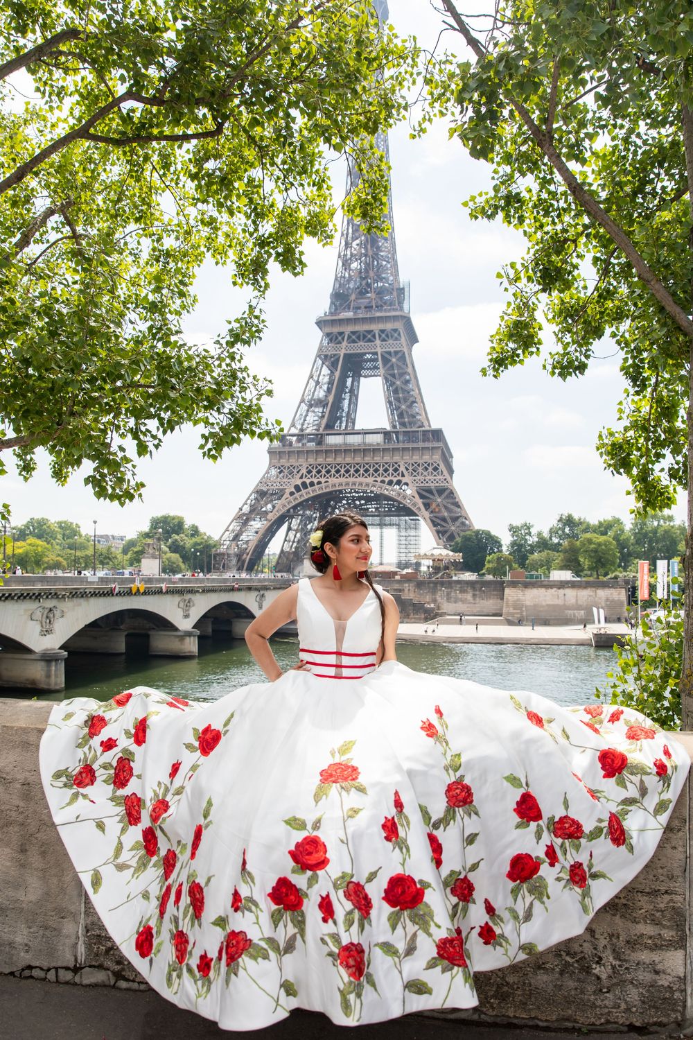 A flowing white dress with red floral details twirls against the backdrop of the iconic Eiffel Tower in Paris.