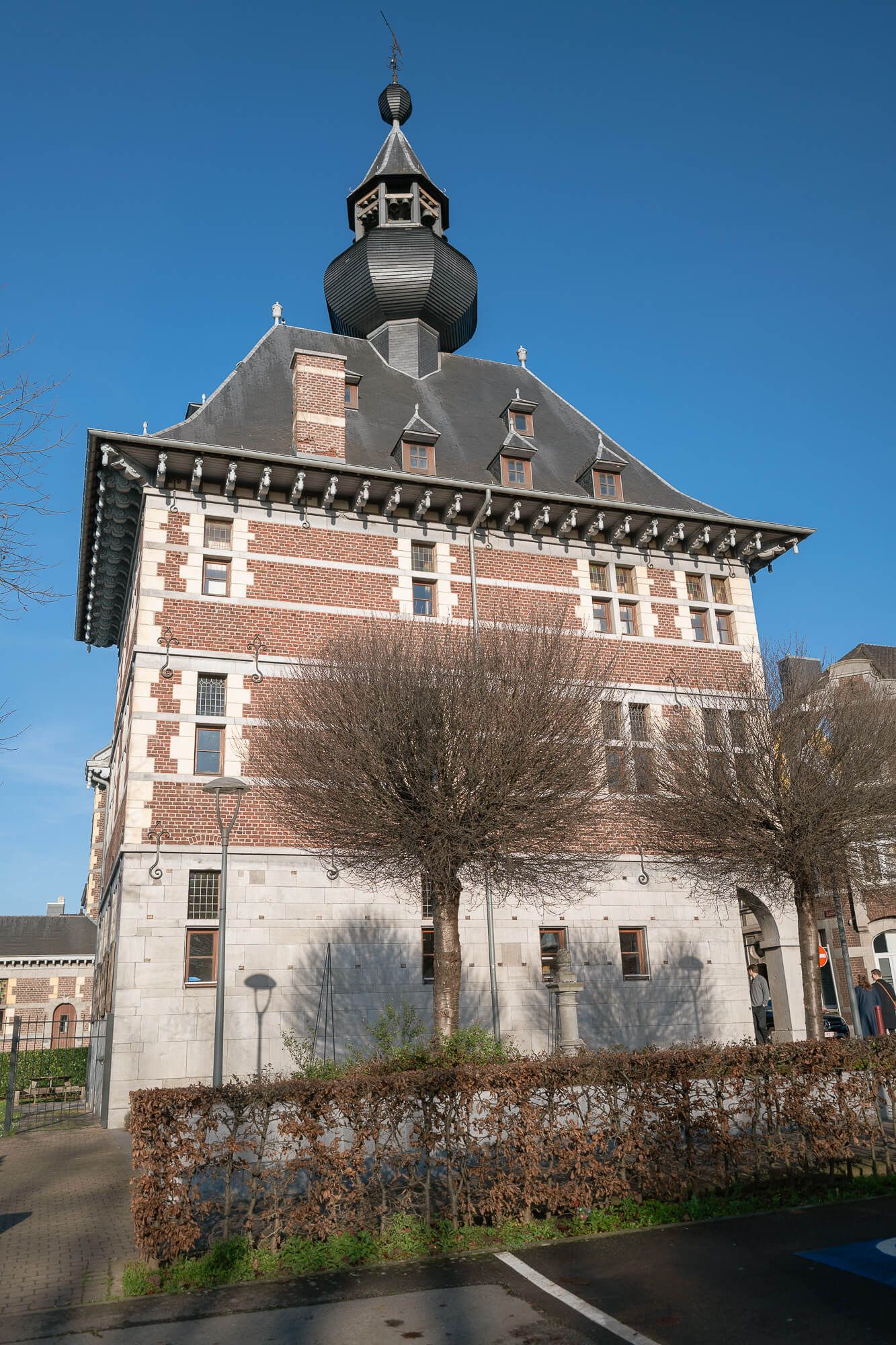 Historic brick building with ornate architectural details and cupola shown from multiple angles against a clear blue sky.