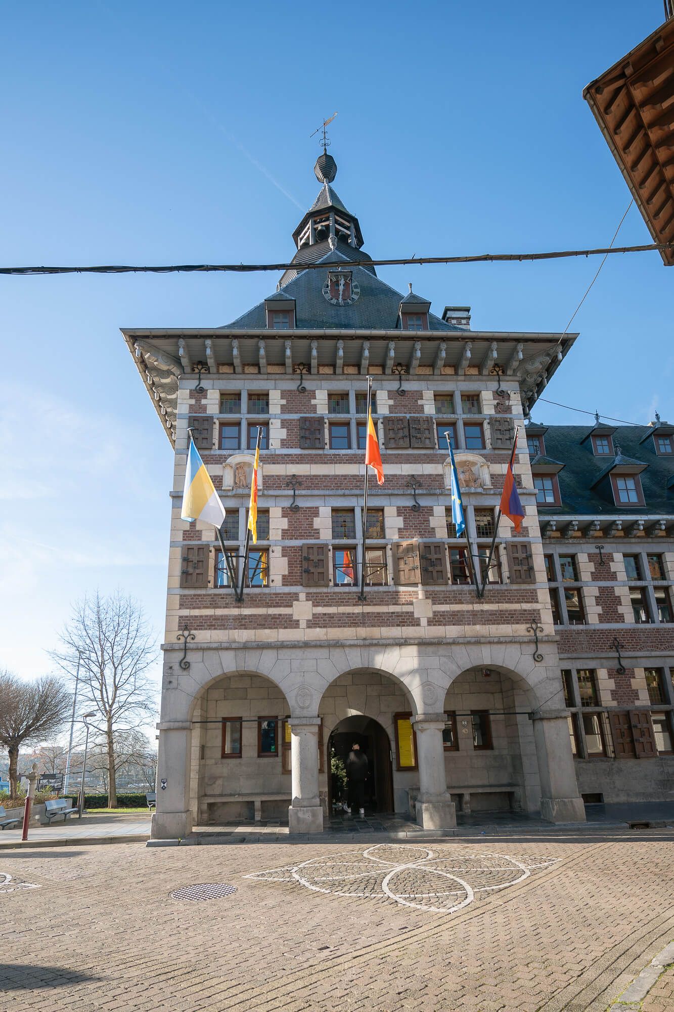 Historic town hall building with arched entrance and ornate architectural details viewed from different angles on cobblestone plaza.