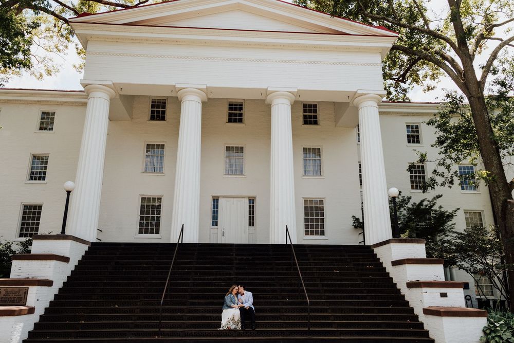 A couple sits on the steps of a grand white colonial building at Gettysburg College for engagement photoshoot