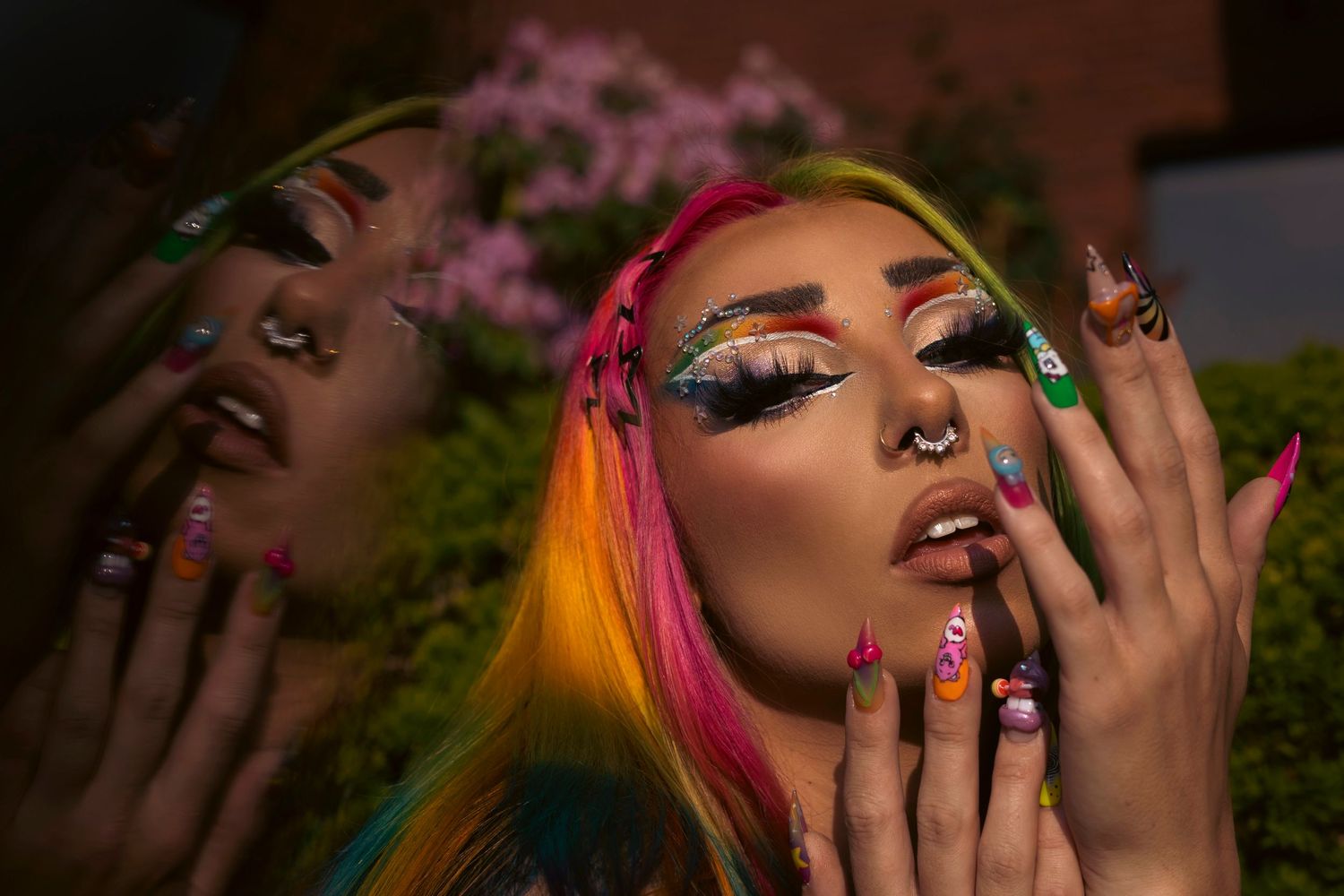 Art photo collage showing expressive poses, vibrant rainbow hairstyles, and dark painted fingernails against lush greenery.