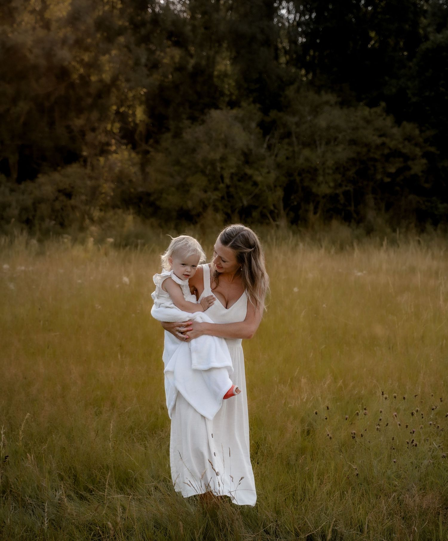 Mother holding her toddler in a wildflower field during a golden hour lifestyle photography session in Derbyshire, capturing natural connect