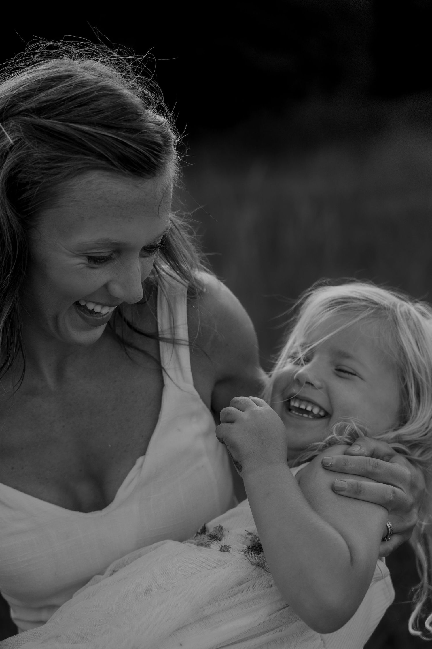 Close-up of a mother holding and laughing with her daughter during a golden hour outdoor lifestyle family session in Derbyshire.
