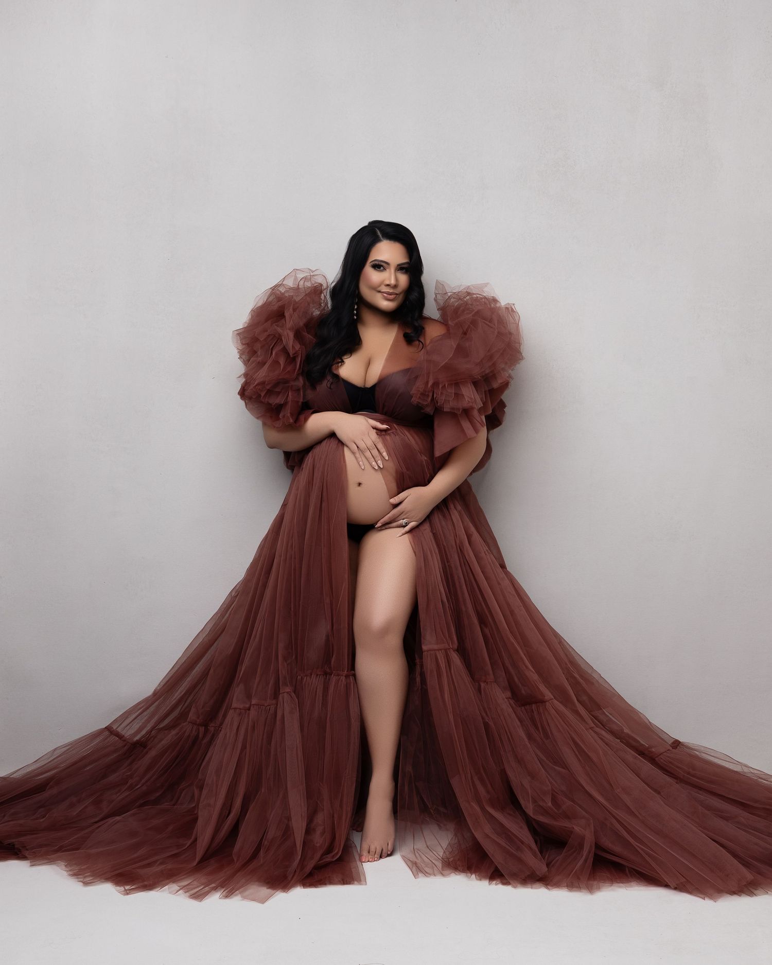Fashion photo of a model in a dramatic burgundy tulle gown flowing across multiple poses against a light gray backdrop.