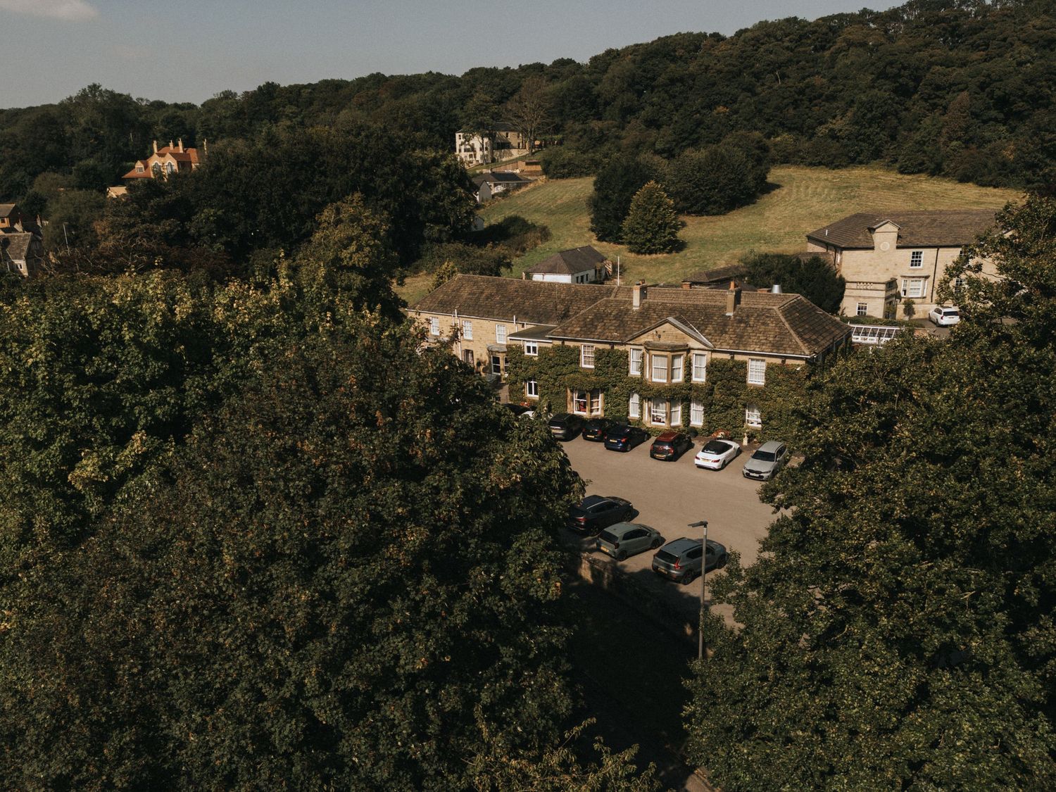 Aerial view of a charming countryside hotel nestled among rolling hills and lush trees.