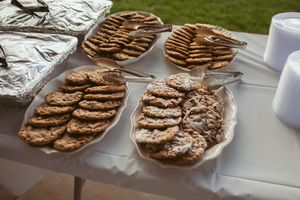 Plates of homemade chocolate chip cookies arranged on a table covered with a white tablecloth.