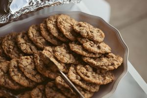 Homemade chocolate chip cookies arranged on a brown ceramic platter with a patterned edge.