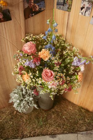 Beautiful floral arrangements with roses and delicate wildflowers displayed in rustic vases against a wooden backdrop.