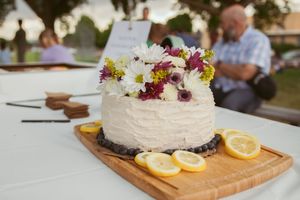 A rustic wooden board topped with a white cake and lemon slices sits on a restaurant table.