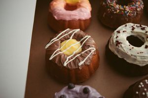 Assorted gourmet donuts decorated with colorful sprinkles, glazes and icing lined up in a display.