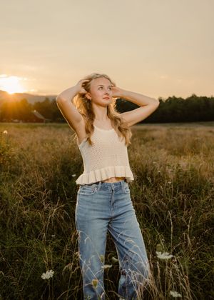 Golden hour portrait series in casual jeans and tank top at sunset in a grassy field.