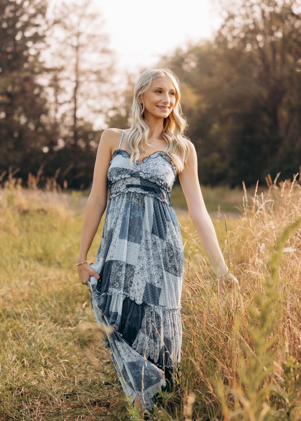 Artistic portrait series in a blue patterned dress against golden sunset lit grass.