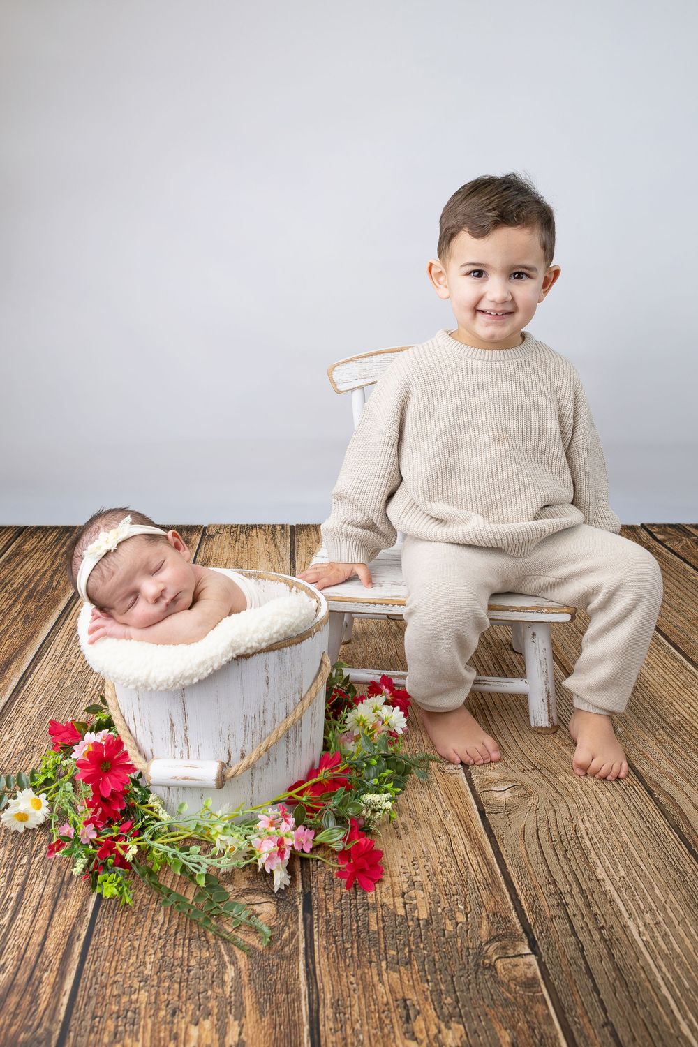 A series of milestone baby photos with cream-colored outfits and floral decorations on rustic wooden flooring.