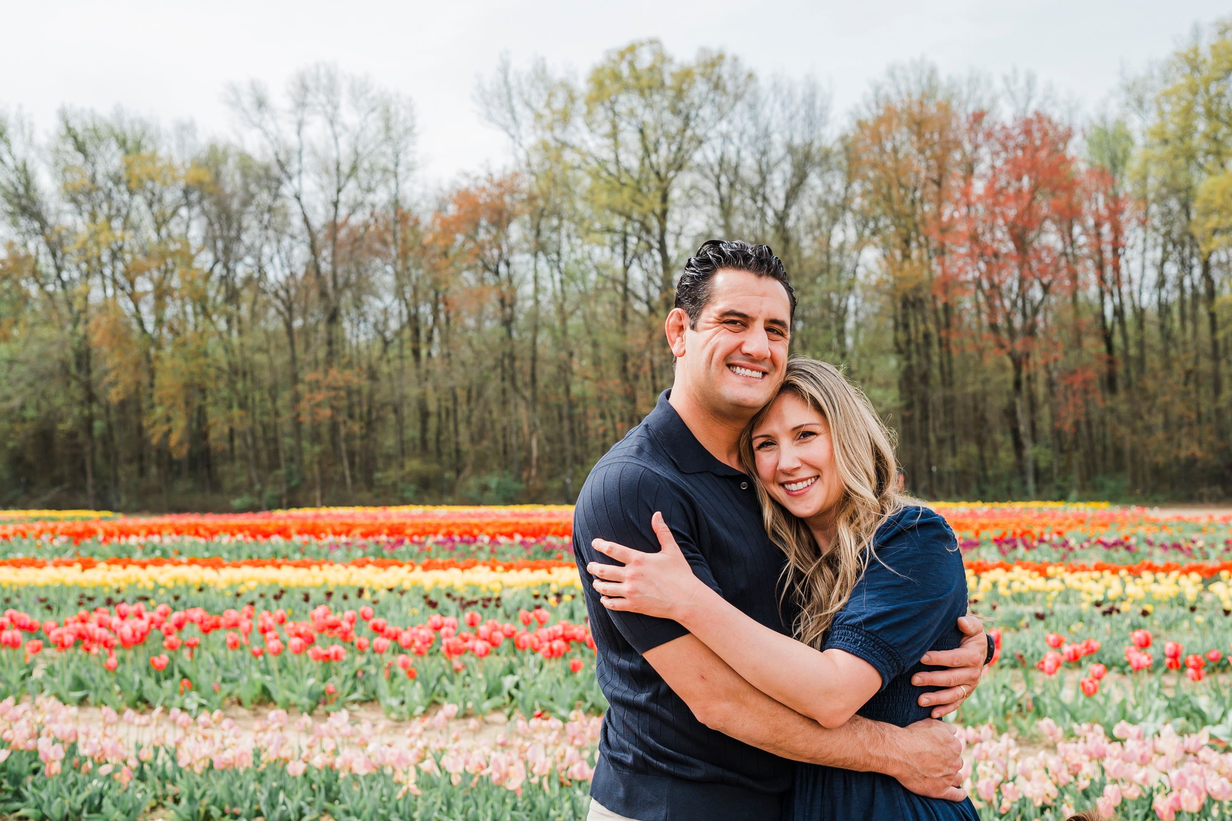 A couple enjoys a tender moment together in a blooming tulip field during autumn.