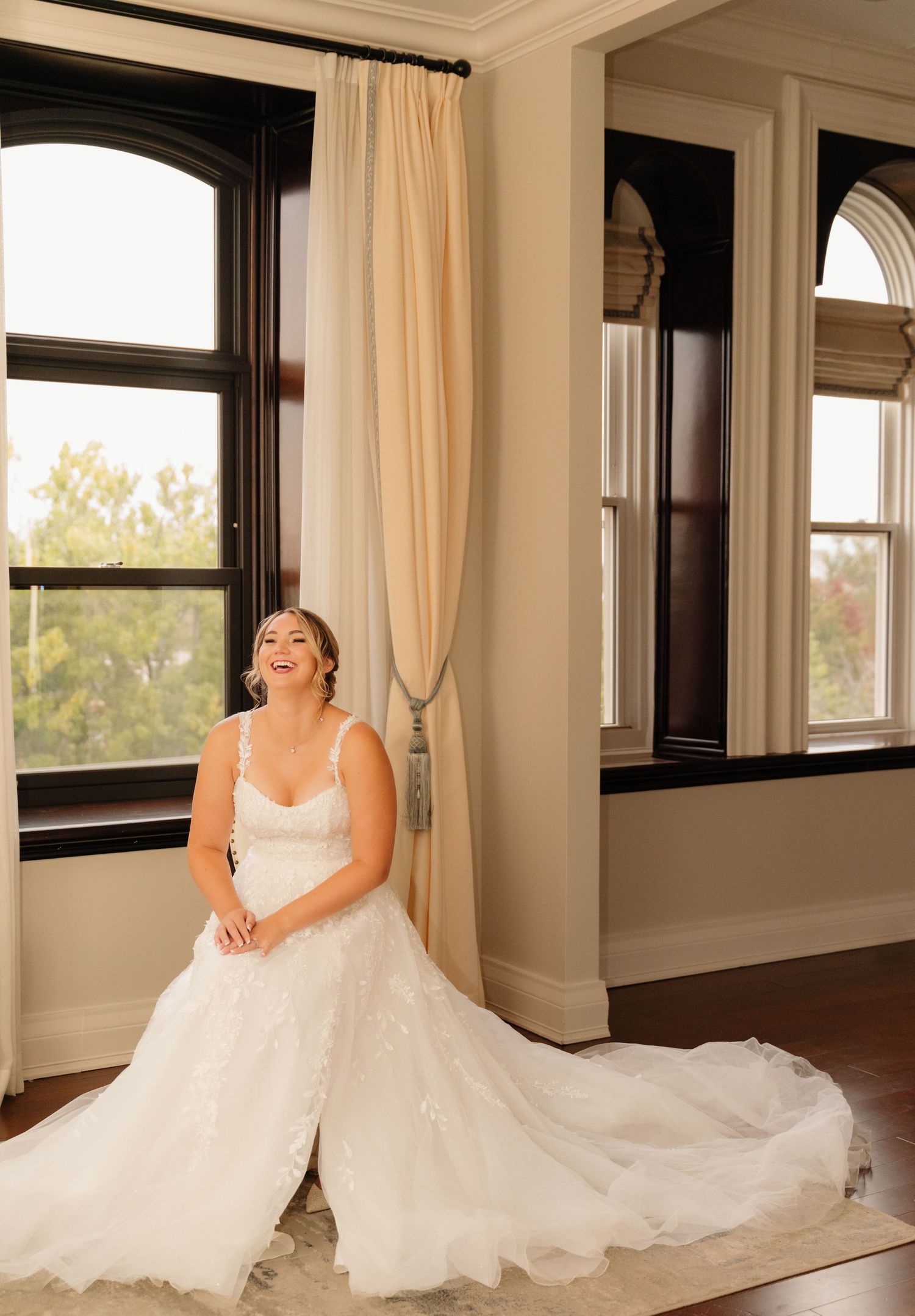 A sunlit room frames a beautiful wedding dress against classic architectural details.