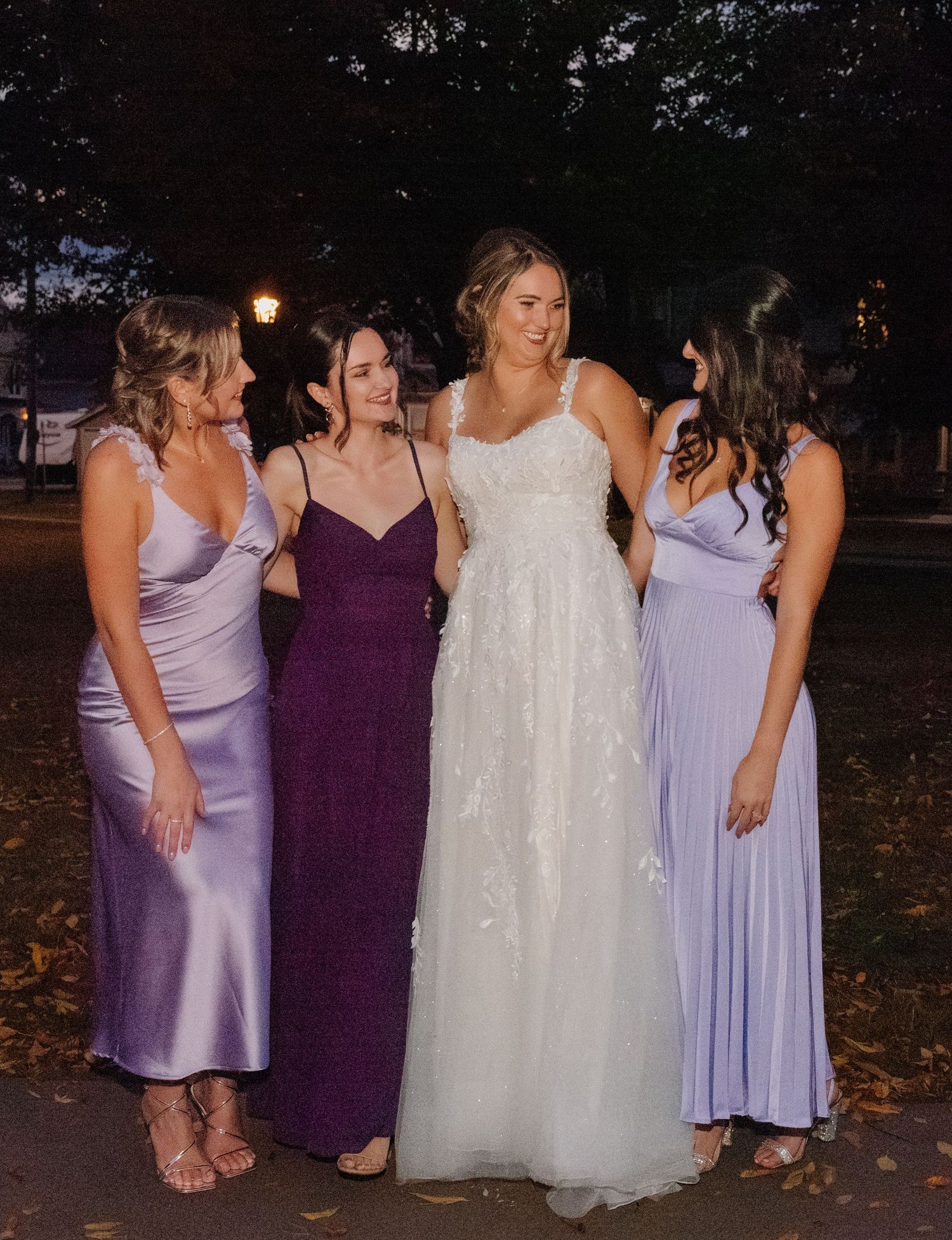 Four attendants in evening formal wear posing outdoors at night.