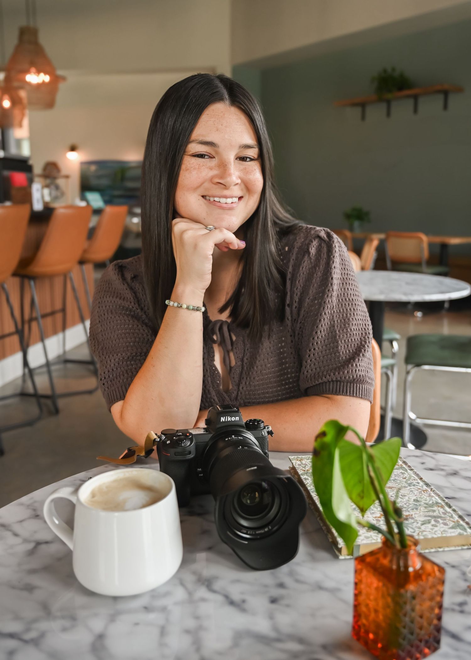 Photographer with camera relaxing at coffee shop with laptop and drinks.