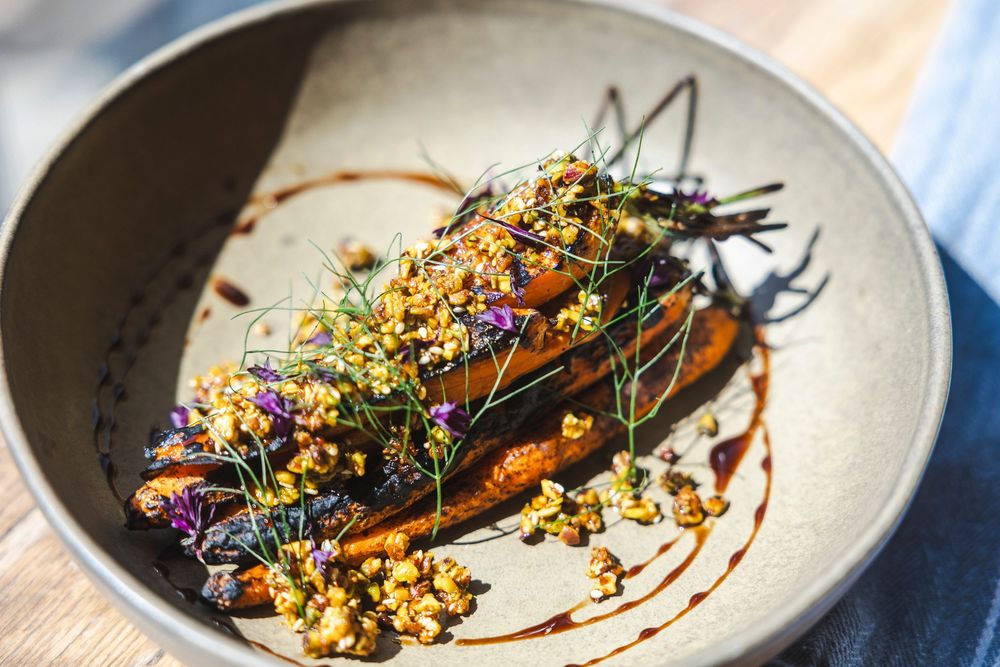 Grilled fish fillet garnished with fresh herbs and colorful edible flowers on a white plate.