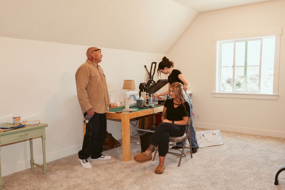 Two people in a minimalist white room during an informal work meeting while seated at a wooden desk.
