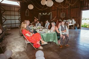Wedding guests seated at tables in a rustic barn venue with paper lanterns and decorative lighting.