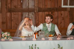 Newlyweds share drinks together at rustic barn reception.