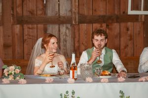 Candid moment captured during wedding reception toasts in rustic barn setting.