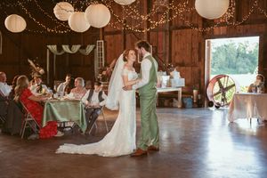 First dance moment at rustic barn wedding reception decorated with string lights and paper lanterns.