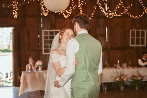 Intimate dance moment in a barn wedding venue illuminated by warm string lights.