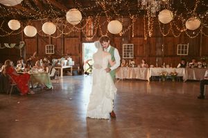 Newlyweds sharing a romantic dance in a rustic barn reception space with elegant decor.