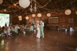 Couple sharing a dance moment in rustic barn venue with paper lanterns and string lights.