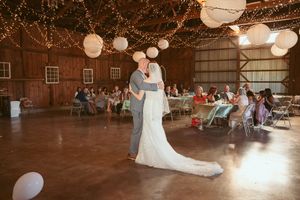 A lively dance celebration at a barn wedding reception with fairy lights and paper lanterns creating ambiance.
