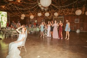 Wedding guests dancing on a rustic barn floor decorated with string lights and paper lanterns.