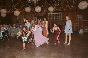 Guests enjoying themselves on the dance floor at a barn wedding with twinkling lights overhead.