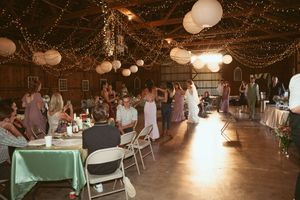 Reception venue decorated with twinkle lights and paper lanterns as guests enjoy the celebration.