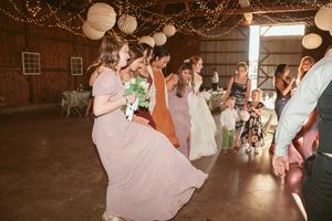 Wedding celebration with dancing guests under string lights and paper lanterns in rustic barn venue.