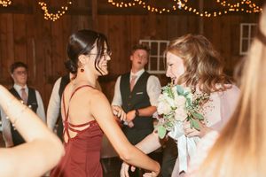 People dancing and celebrating at a rustic barn wedding reception under string lights.