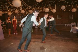 Couples dance at a rustic outdoor evening event with glowing paper lanterns hanging from above.