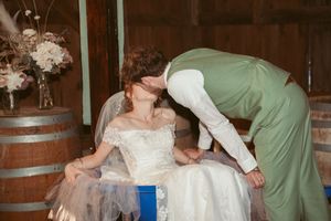 A romantic moment shared between a couple among wine barrels at a rustic wedding venue.