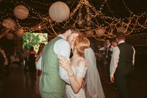 Romantic dance under string lights and paper lanterns at rustic barn wedding reception.