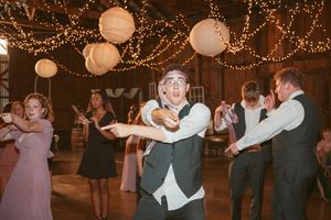 Wedding guests dancing and celebrating under festive string lights and paper lanterns.