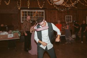 Dancing guest showing off moves at a barn wedding reception under string lights.