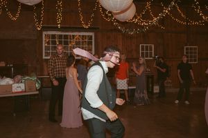 Guests dance together in a rustic barn venue with string lights overhead during an evening celebration.