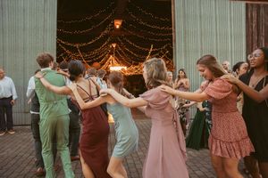 People dancing in a line at a celebration with string lights illuminating the venue.