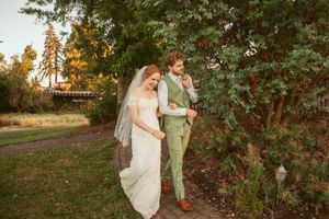 Couple walking together through a scenic autumn garden path during golden hour at a wedding celebration.