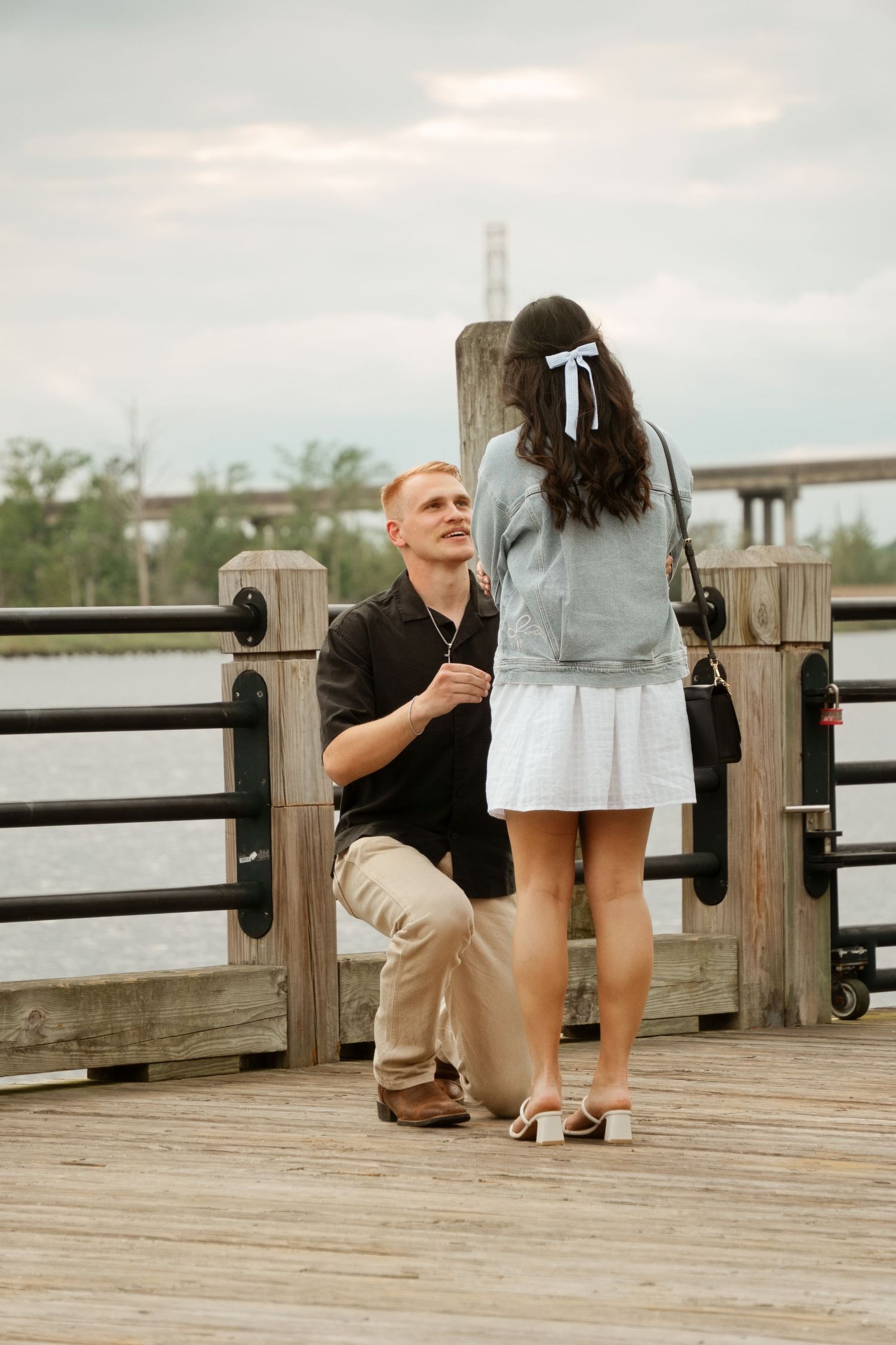 A romantic proposal moment on a wooden boardwalk.