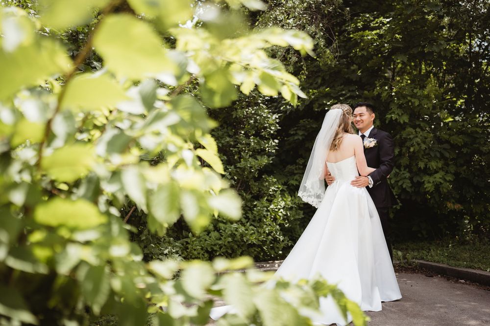 Two people sharing a romantic moment in a garden setting surrounded by lush greenery and natural sunlight.