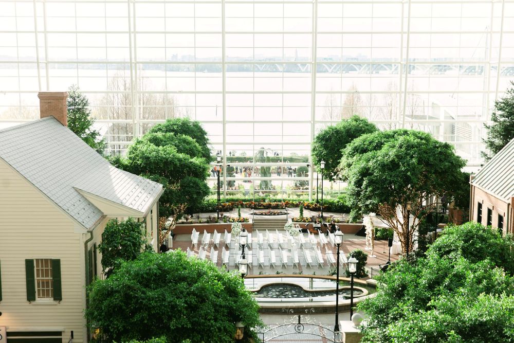 Aerial view of a landscaped courtyard with water features and green trees between white buildings.
